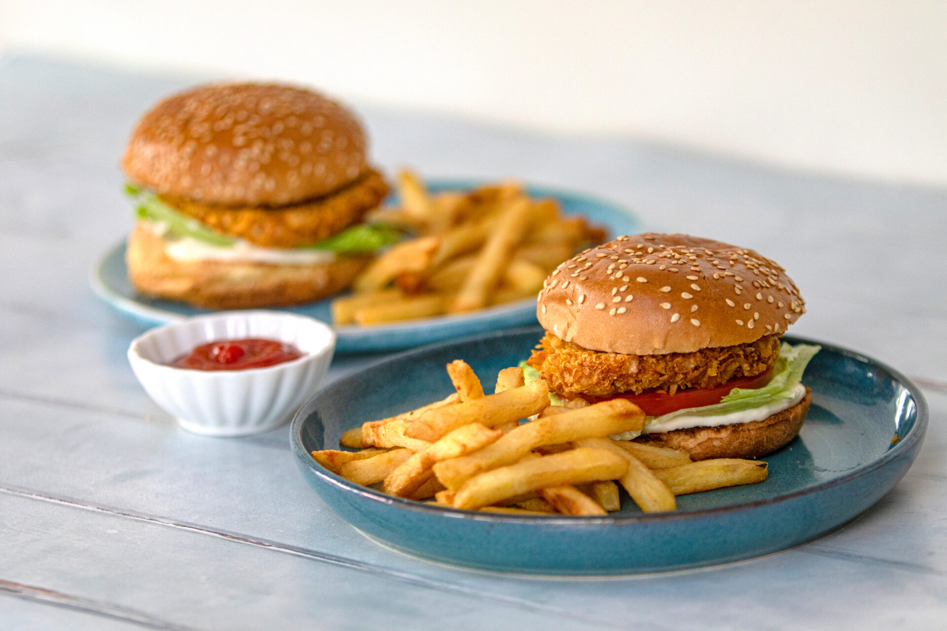 A crispy pork burger on a plate with chips