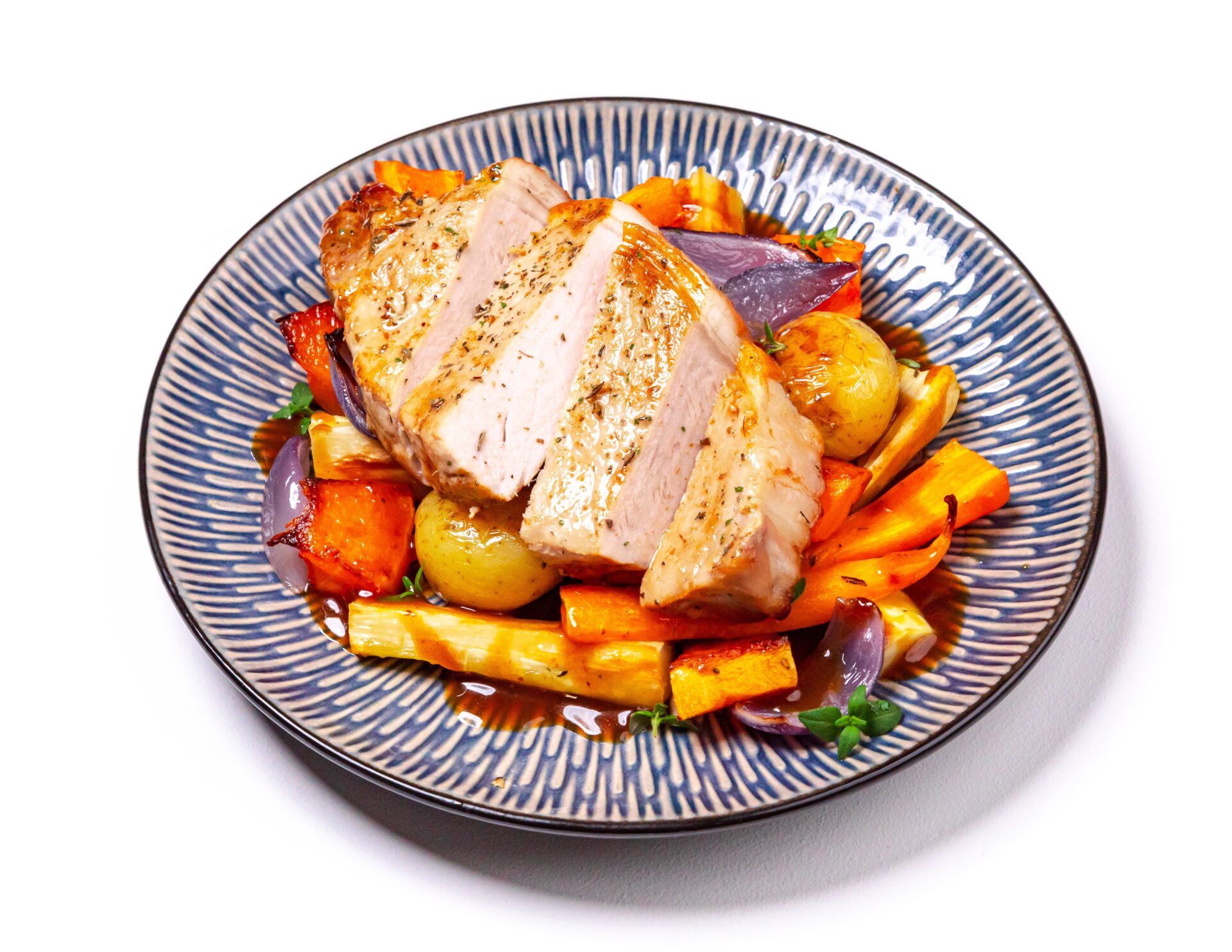 Air fried pork steaks with roasted parsnips, carrots and butternut squash on a blue patterned plate